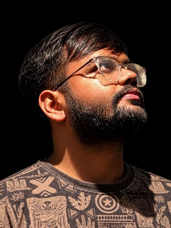 Ayush Shah looking up, wearing glasses and a patterned T-shirt